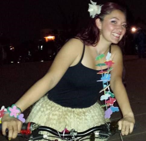 Foto de mujer sobre bicicleta sonriendo con tutú amarillo y camiseta negra 