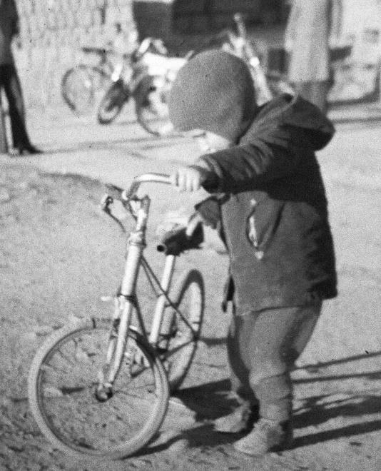 Fotografía en blanco y negro de un niño pequeño a punto de montar una bicicleta.