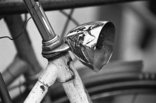 Foto en blanco y negro, detalle de lámpara frontal metálica de bicicleta estropeada de estilo antiguo